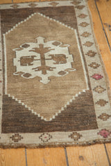 Repeating stepped diamond border of vintage Oushak rug in brown, ivory, and blush pink.