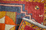Thick red, blue, yellow hand-knotted pile, revealing its woven foundation and ivory fringe.