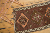 Vintage Oushak rug corner detail with thick plum brown pile, tangerine diamond, and ivory border.