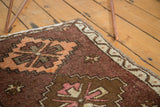 Corner of vintage Oushak rug with plum brown field, tangerine diamond motifs and ivory border.