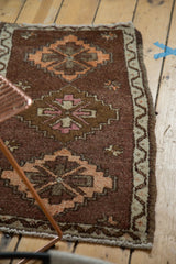 Vintage Oushak rug corner showing wavy ivory border and tangerine diamond medallion on plum brown.