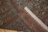 Folded Vintage Shiraz carpet showing geometric patterns, secured edge, and hand-knotted reverse.
