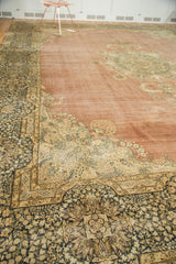 Distressed Kerman carpet corner, pale blush field and intricate navy, ivory milfleur spandrels.