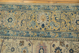 Distressed vintage Persian carpet with saffron, navy, and rose stylized motifs.