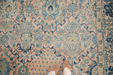Blush and blue ornate vase motifs with scrolling vinery on a vintage Kashan rug.