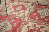 Cherry red quatrefoil serrated leaf motifs with saffron yellow and grey on a vintage Oushak.