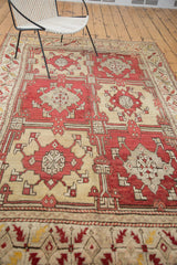 Vintage Oushak carpet section featuring cherry red and ivory geometric florals and patterned border.