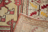 Vintage Oushak carpet close-up, featuring cherry red quatrefoil motif, pale saffron, and woven foundation.
