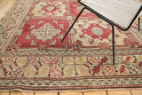 Vintage Oushak rug's geometric border in saffron, grey, and red patterns next to main field.