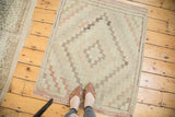 Turkish Jijim rug with faded geometric diamond square pattern in ivory, sea foam, and blush tones.