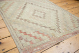 Faded ivory and blush geometric pattern on vintage Turkish Jijim rug with secured edge.