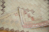 Folded vintage Turkish Jijim rug, geometric diamond pattern, faded ivory, blush, seafoam green, secured edge.