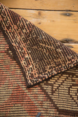 Folded vintage Jijim carpet, showing hand-woven back and textured front in brown, red, ivory.