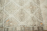 Distressed silver and ivory geometric pattern with a visible hole on the vintage Jijim rug.