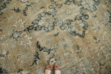 Distressed vintage Persian Tabriz rug, intricate faded indigo, charcoal, and sand floral patterns.