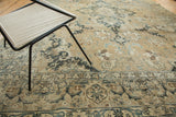 Distressed vintage Tabriz carpet displaying intricate faded blue, sand, and brown floral patterns.