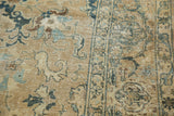 Faded indigo, sand, and charcoal floral patterns with distressed texture on a vintage Tabriz rug.