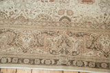 Ornate blush and ivory curvilinear border of a distressed Tabriz carpet, showing even pile wear.