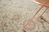 Distressed vintage Tabriz rug featuring soft ivory, blush, and pale green floral motifs.
