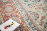 Distressed Kaisary rug with faded palmette and ribbon motifs in teal, pomegranate red, and ivory.