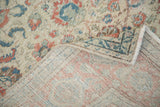 Curled corner of vintage distressed Kaisary rug, showing faded floral motifs and hand-knotted back.