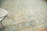 The distressed pile texture featuring faded ink blue vinery and brilliant terra cotta border.