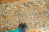 Distressed vintage Oushak runner with faded tangerine geometric medallion and muted tones.
