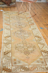 Corner of distressed Oushak runner, highlighting stepped geometric patterns and faded tangerine hues.