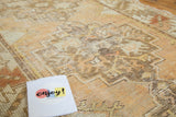 Textured distressed vintage Oushak rug showing softened tangerine and saffron geometric patterns.
