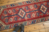 Close-up of Turkish Dosmealti runner's cherry red field, blue floral stem, ivory medallion, barber pole border.