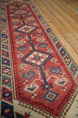Cherry red field showcasing blue floral stem, ivory medallion, and geometric border detail.