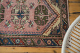 Geometric blush field with starbursts and barber polled border of a vintage Turkish runner.