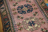 Blush field of vintage Dosmealti runner showing geometric rams horn medallion and barber polled border.