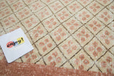 Textural detail of the distressed blush and ivory quatrefoil lattice Oushak rug.