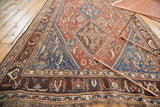 Detailed border and distressed herati motif of an antique Qashqai rug with chestnut brown and sky blue.