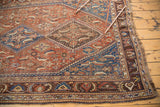 Traditional tribal patterns and border detail of an antique Qashqai rug in chestnut, sky blue, and saffron tones.