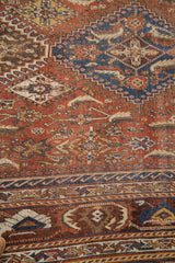 Antique Qashqai rug's lower border, distressed geometric patterns in chestnut, sky blue, charcoal.