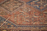 Distressed hand-knotted herati motif in chestnut, sky blue, and saffron on an antique Qashqai rug.