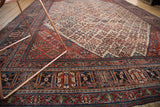 Intricate patterns of a distressed vintage Joshegan carpet, showcasing fine weave, brick red, and navy blue.