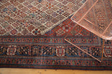Distressed vintage Joshegan carpet, corner detail showing navy blue border and traditional field motifs.