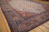 Joshegan style carpet's intricate brick red and navy borders, with a subtle patina.
