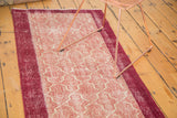 Distressed texture of a vintage Konya runner with wine red border and cochineal tile pattern.