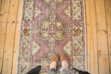 Distressed Oushak rug runner showing faded eggplant purple field and geometric medallion.