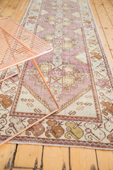 Distressed vintage Oushak runner featuring eggplant purple, gold, and ivory geometric motifs.