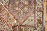 Distressed hand-knotted Oushak runner, eggplant purple field with blanched gold and green geometric border.