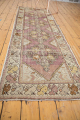 Distressed Oushak runner fringe and textured border with blanched gold, chocolate, and eggplant motifs.