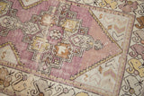 Close-up of vintage distressed Oushak runner, showing faded eggplant field and geometric motifs.