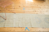 Repeating faded silver-grey medallions on the antique ivory vintage Oushak runner.