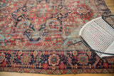 Distressed antique Heriz carpet with cherry red field, light blue abrashed details, and a navy geometric border.