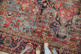 Distressed antique Heriz carpet showing cherry red field with light blue geometric vinery.